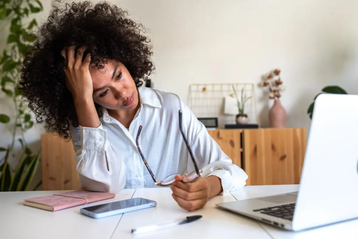 stress-vs-anxiety-1200×800 A stressed woman holds her glasses in her hands as she stares at her laptop